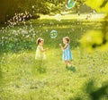 Little girls blowing soap bubbles on a summer meadow Royalty Free Stock Photo