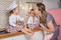 Little girls in chef hats with mother in apron is playing chefs. Royalty Free Stock Photo