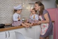 Little girls in chef hats with mother in apron is playing chefs. Royalty Free Stock Photo