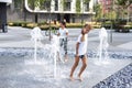 Little girls cool off in a fountain on a hot summer day.