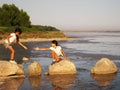 Little girls crossing the river over rocks