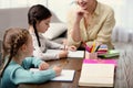 Little girls doing homework with mother at table Royalty Free Stock Photo