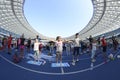 Little girls doing morning exercises on the stadium, adult on a background