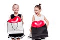 2 little girls with elegant dresses hold large bags with heart-shaped balloons inside Royalty Free Stock Photo