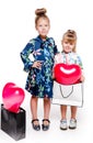 2 little girls with elegant dresses stay next to large bags with heart-shaped balloons inside Royalty Free Stock Photo