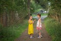 Little girls excitedly talking standing in the green alley.