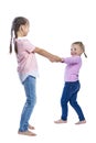 Little girls hold hands and run happily. Children with pigtails in pink sweaters and jeans. Energy and activity in children`s