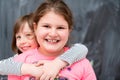 Little girls hugging in front of chalkboard Royalty Free Stock Photo