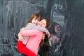 Little girls hugging in front of chalkboard Royalty Free Stock Photo