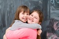 Little girls hugging in front of chalkboard Royalty Free Stock Photo