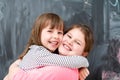 Little girls hugging in front of chalkboard Royalty Free Stock Photo