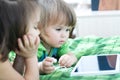 Little girls looking on pad lying on bed. Children time spending. Kids using tablet computer Royalty Free Stock Photo