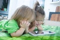 Little girls looking on pad lying on bed at home. Children time spending. Kids using tablet Royalty Free Stock Photo