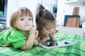 Little girls looking on pad lying on bed at home. Children time spending