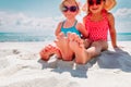 Little girls play with sand on beach vacation