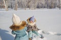 Little girls play in a snow in a winter park