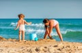 Little girls playing in the sand on Black Sea coast beach at Anapa resort while spending family vacation Royalty Free Stock Photo