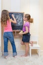 Little girls in the playroom paint on the blackboard