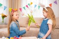 little girls with a red headband and rabbit ears hold pink tulip flower in hands