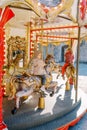 Little girls ride a toy horses on a colorful carousel. Back view