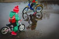 Kids riding bike in spring water puddle Royalty Free Stock Photo