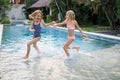 Little girls running in the swimming pool. Sisters playing together. Summer concept. Family activities. Happy childhood. Vacation