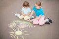 Little sisters draw with color chalk outdoors. Chalk drawings.