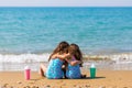 Little girls sit back on the sand and cuddle, together with cocktails. Family vacation concept. happy sisters Royalty Free Stock Photo