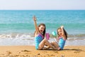 Little girls sit sit opposite each other, drink from colored beautiful cocktail glasses and have fun. Family vacation