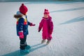 Little girls skating together in snow, kids winter activities Royalty Free Stock Photo