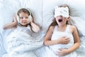 Little girls sleep in bed. One is snoring hard,sister is plugging ears with fur headphones.Early morning wake up,rise to Royalty Free Stock Photo