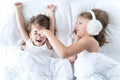 Little girls sleep in bed. One is snoring hard,sister is plugging ears with fur headphones.Early morning wake up,rise to Royalty Free Stock Photo