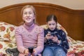 Little girls with smartphone watch TV. The girl in front of the TV looking in the smartphone