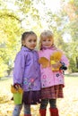 Little girls in waterproof coats and boots in autumn park