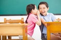 Little girls whispering and sharing a secret in classroom Royalty Free Stock Photo