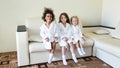 Three girls of different nationalities are sitting on the couch.