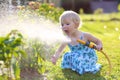 Little giving water to flowers in the garden