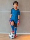 Little goalkeeper boy is standing on soccer football portrait