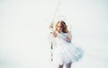 Little goddess with white wings alone on blue sky background. Portrait of little curly blond Angel girl. Girl angel with Royalty Free Stock Photo