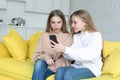 Little gorl in white shirt showing something interessting on smartphone to her sister