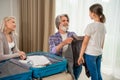 Little granddaughter helping grandfather packing clothes for travel