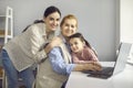 Little granddaughter and her mother tenderly hug her grandmother, who works at home on a laptop. Royalty Free Stock Photo