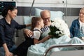 Little granddaughter hugging elderly grandfather visiting him in hospital ward Royalty Free Stock Photo
