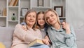 Little granddaughter hugs 60-year-old grandmother and young mother, showing love on Mother's Day, looking at the Royalty Free Stock Photo