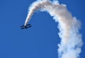Pitts Model 12 stunt byplane with smoke trail and blue sky.