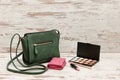 Little green ladies handbag, pink purse, eyeshadow palette and lipstick on wooden background. fashion concept Royalty Free Stock Photo