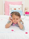 Little gril listening to music lying on her bed