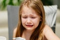 Little grimy girl cries at the dinner table. The child refuses to eat. Royalty Free Stock Photo