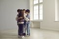 Little group of school children huddling standing together in spacious empty room