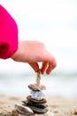 Little Hand placing Stone on the Pyramid on sand. Sea in the bac Royalty Free Stock Photo